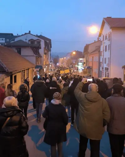 Mnoštvo ljudi na ulici tokom protesta, zgrade u pozadini, večernje svetlo.