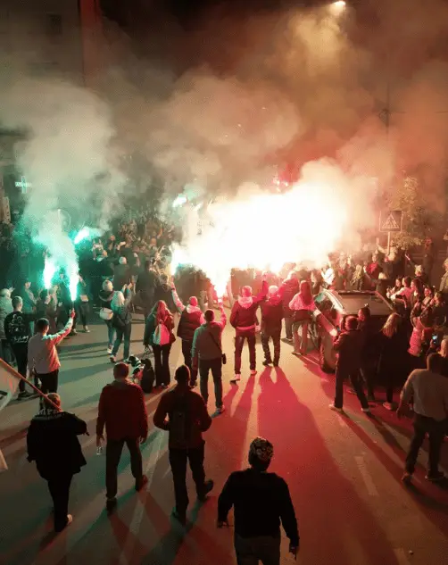 Noćna scena sa ljudima koji nose baklje na dočeku studenata